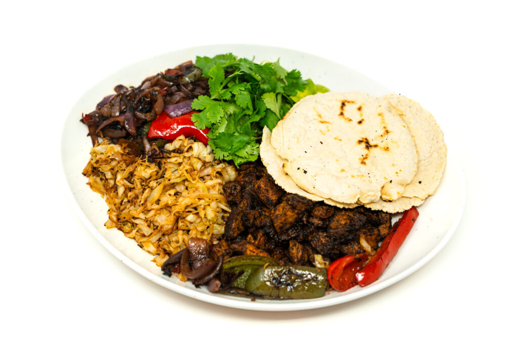 A platter of sliced pork sirloin fajitas with sautéed bell peppers, charred cabbage, and corn tortillas garnished with cilantro.