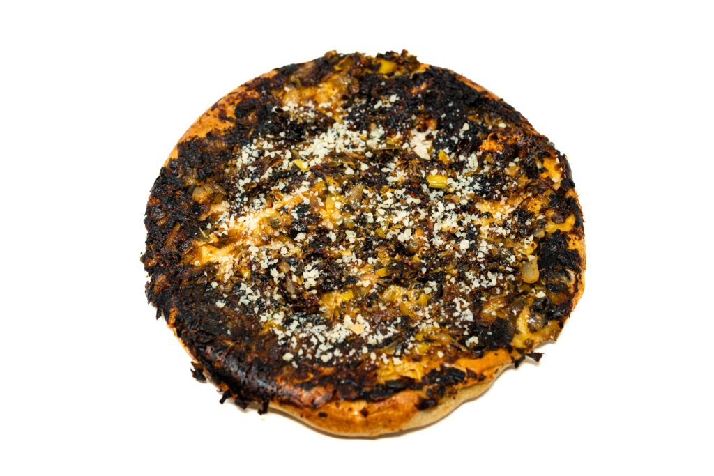 A golden brown caramelized leek and onion pizza tarte tatin topped with parmesan cheese and red pepper flakes.