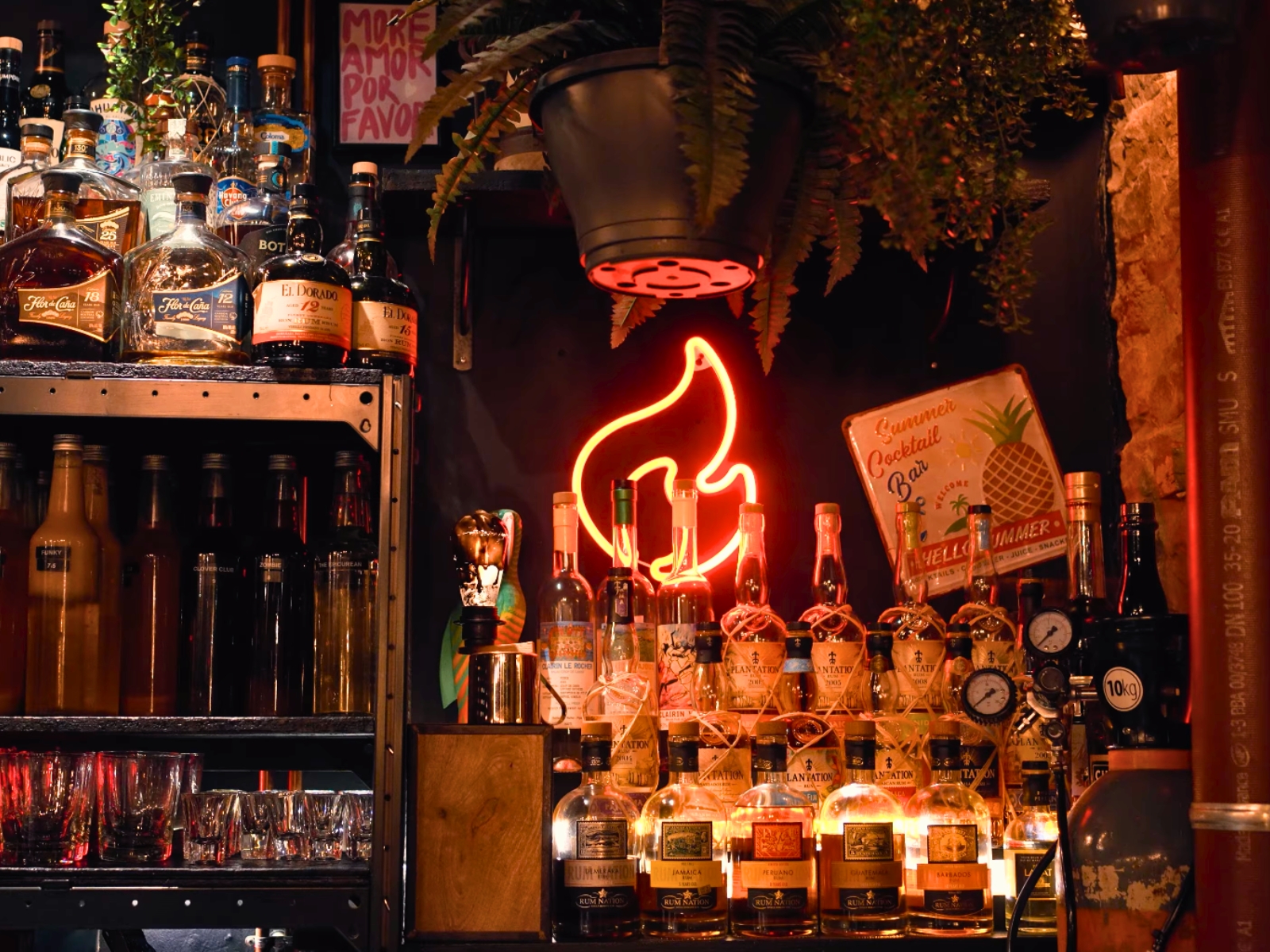 Glowing neon sign and premium spirit bottles at L'Alchimiste mixology bar.