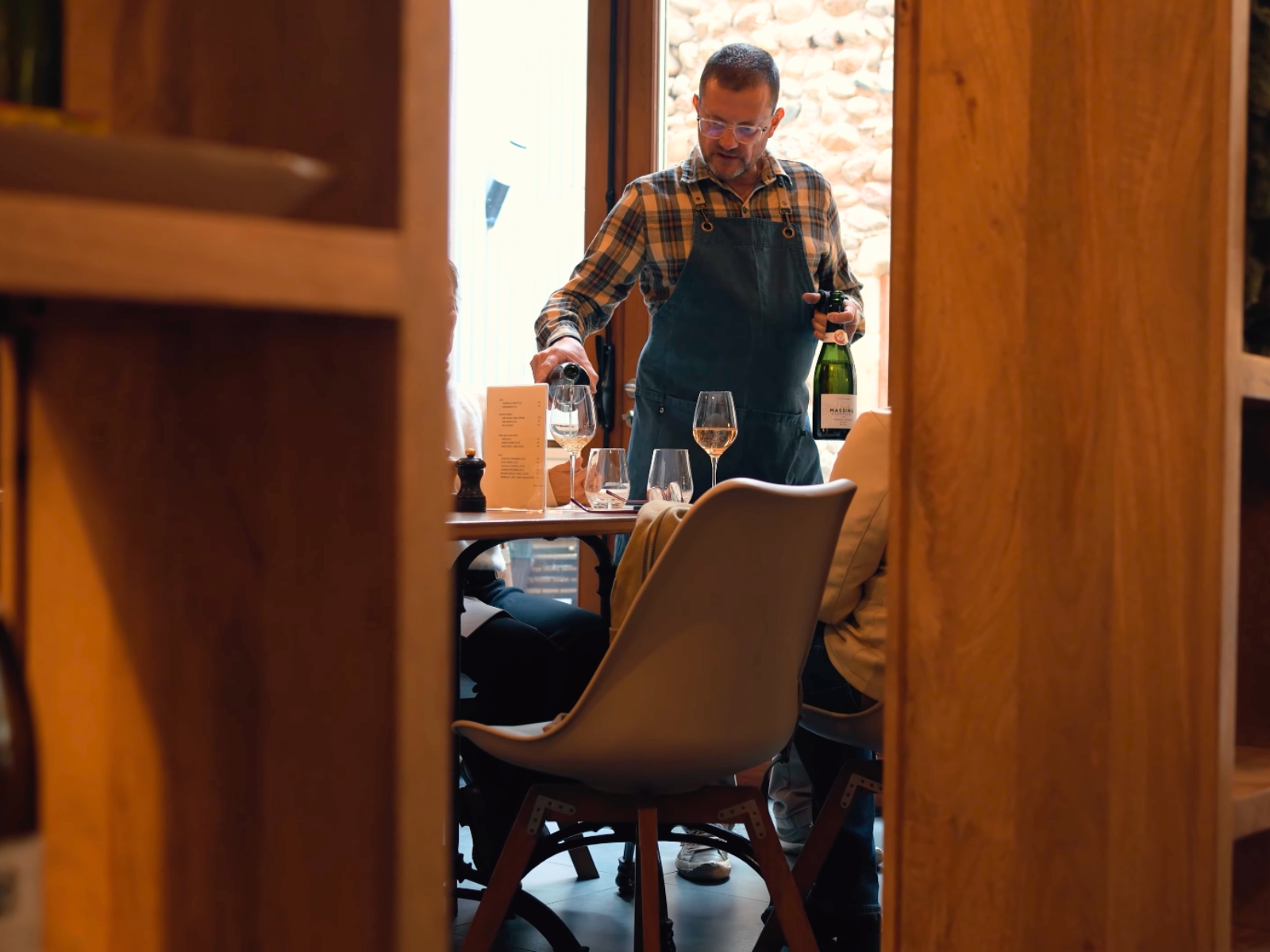 A sommelier pouring a glass of regional wine inside Le Mangevins restaurant.