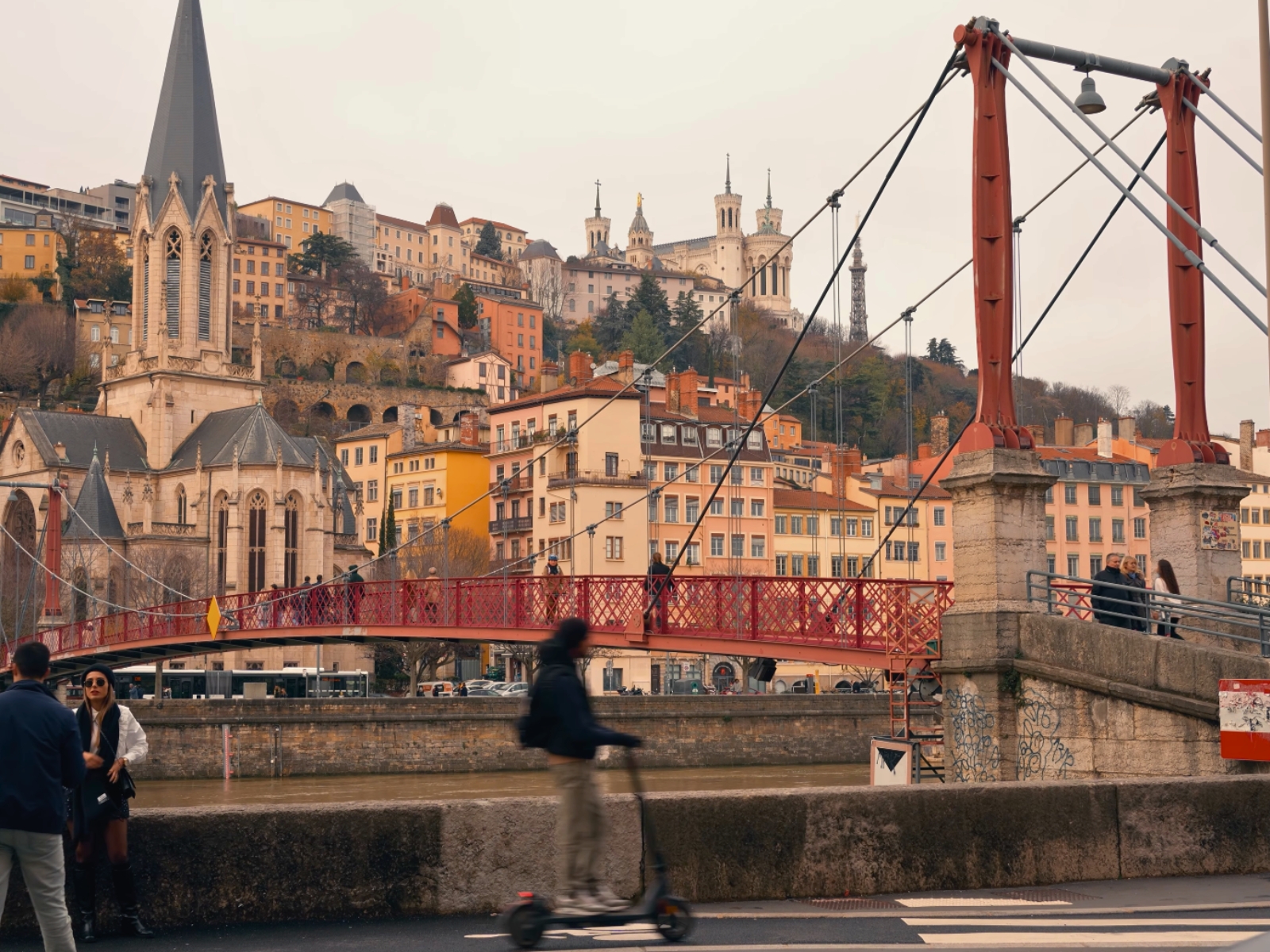 A scenic view of a bridge crossing the Rhône River with the Lyon skyline in the background.