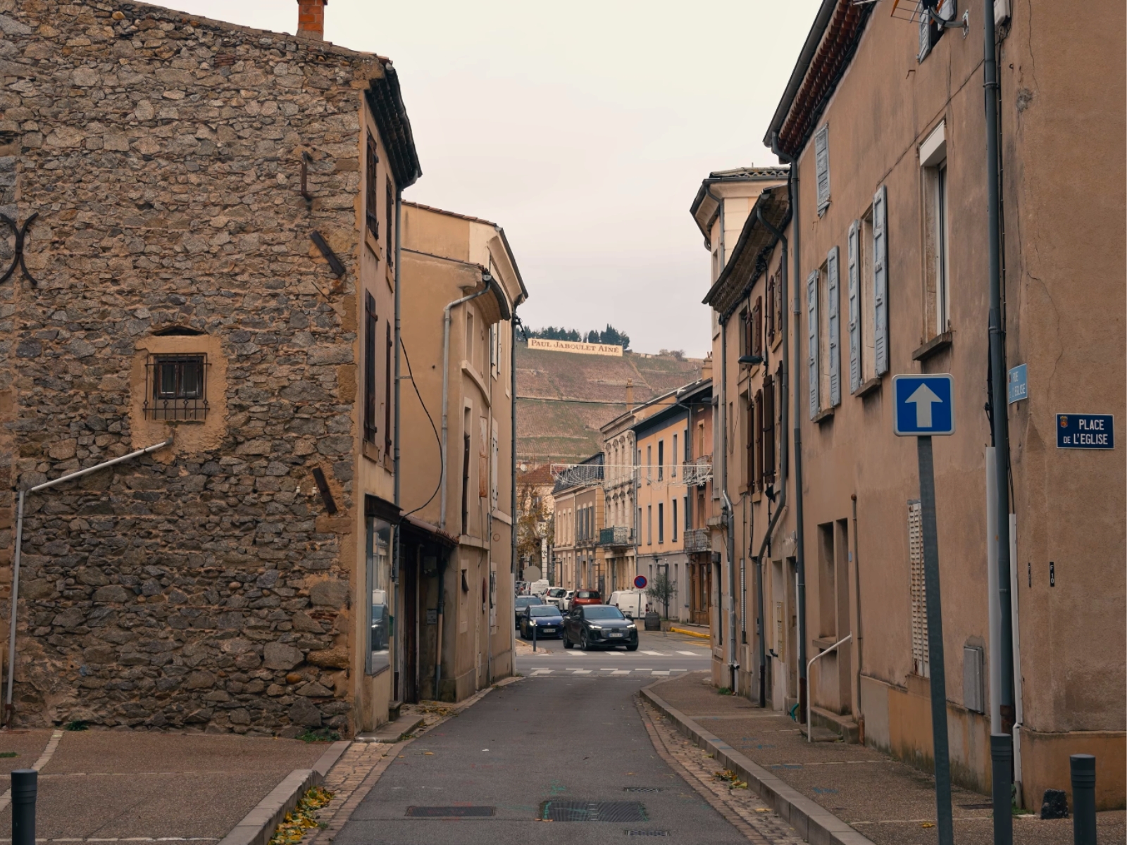 Historic stone buildings lining a narrow street in Tain L'Hermitage, France.