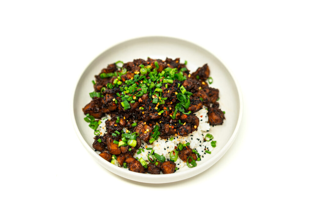 Dark caramelized hot honey garlic sticky chicken thighs served over white sushi rice and topped with bright green scallions.