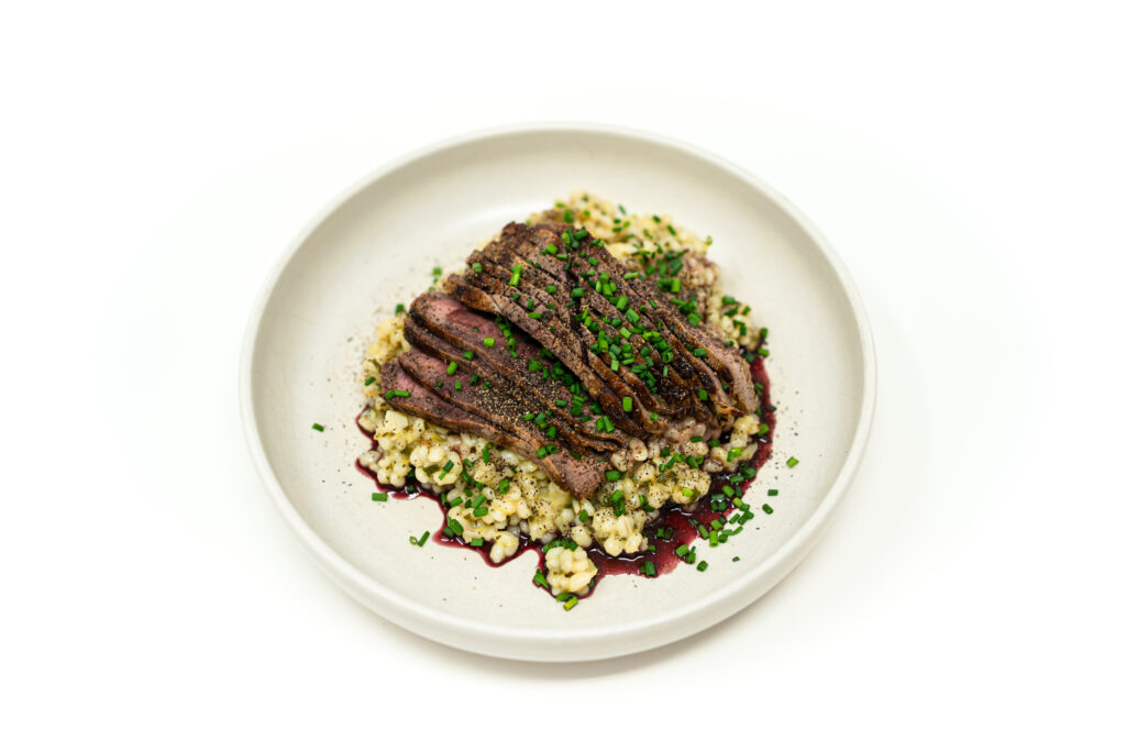 Sliced medium rare cast iron seared London broil over herb dijon barley with a pooled red wine reduction.