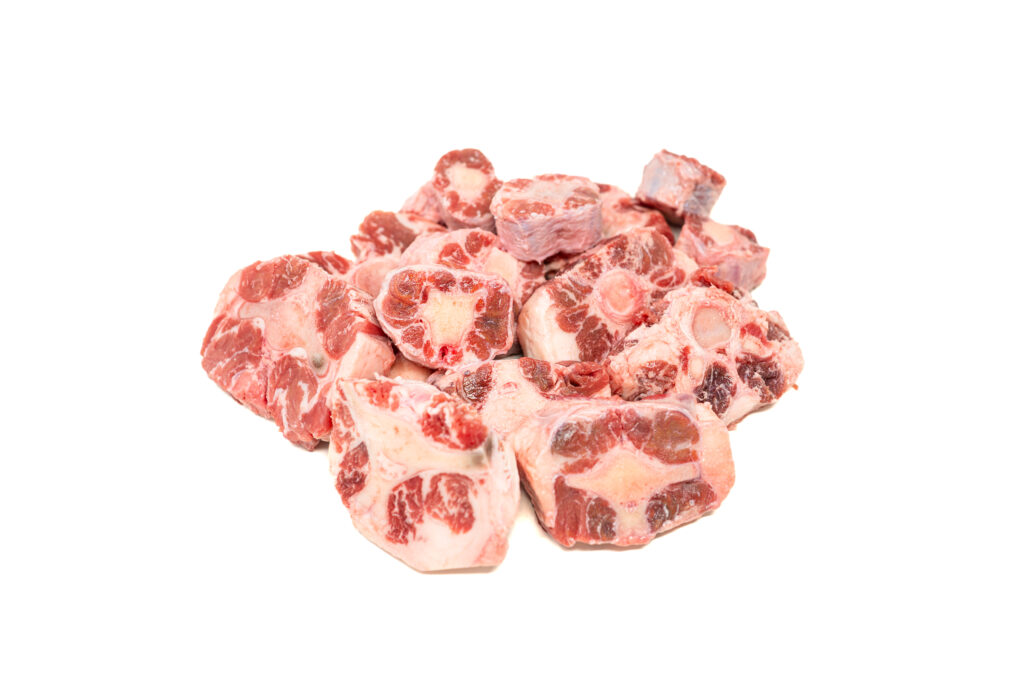 Raw, thick-cut oxtail segments ready for searing and a spiced chipotle-ancho braise.