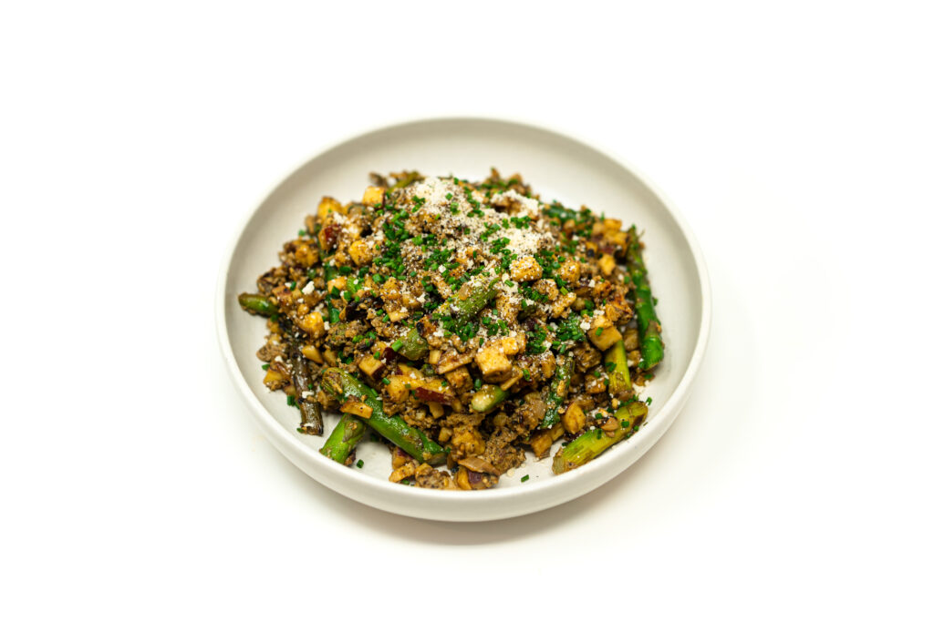 A shallow bowl piled high with a miso-cream egg scramble, caramelized Japanese sweet potatoes, blistered asparagus, and fresh chives.