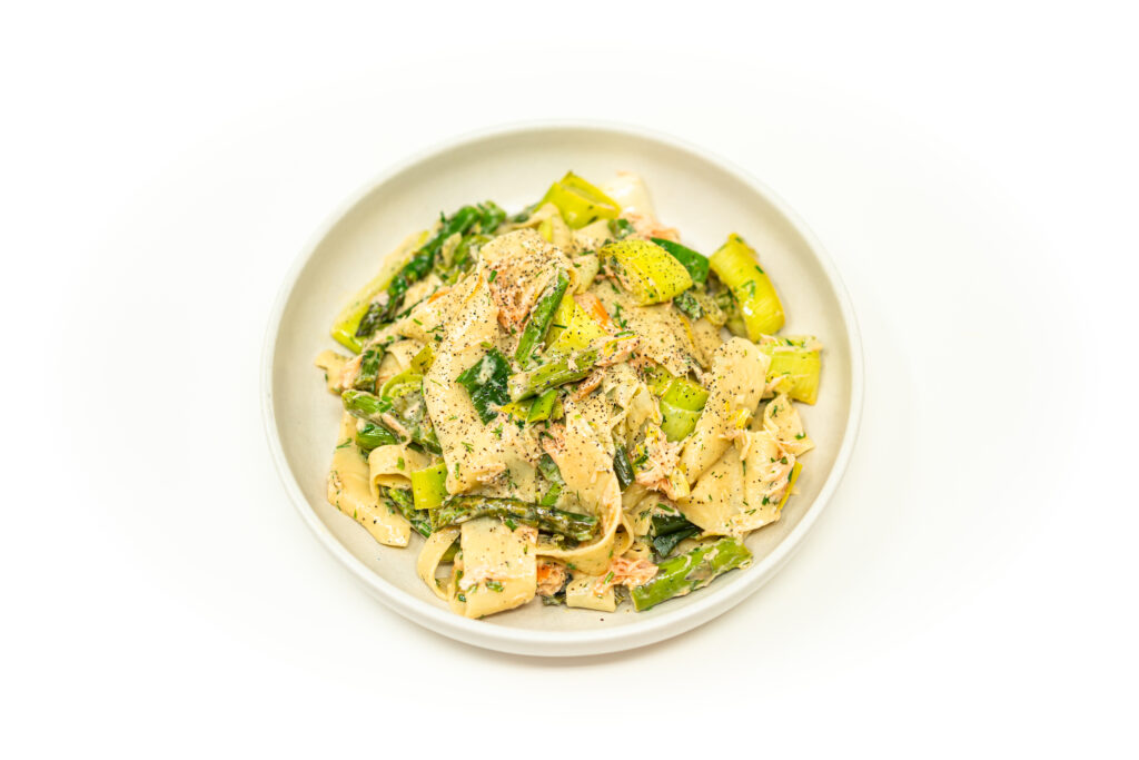 Wide pappardelle noodles coated in a rich citrus cream sauce, tossed with flaked smoked salmon, bright green asparagus, and fresh herbs.
