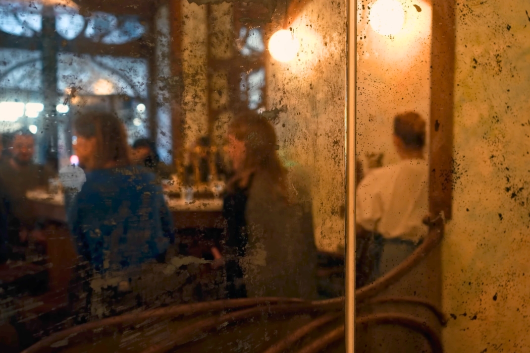 Moody, dimly lit interior showing the bar area and patrons at Bar Nouveau in Paris.