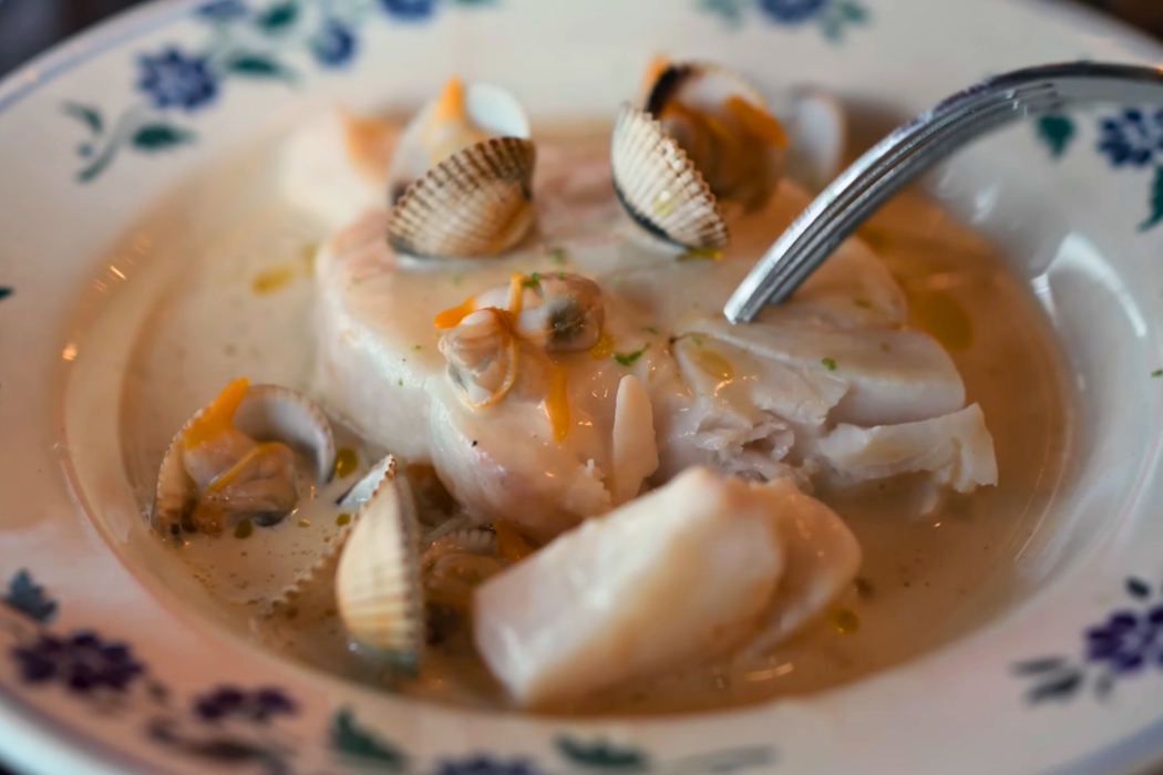 Close-up of a plated seafood and clam broth dish served at Clown Bar in Paris.