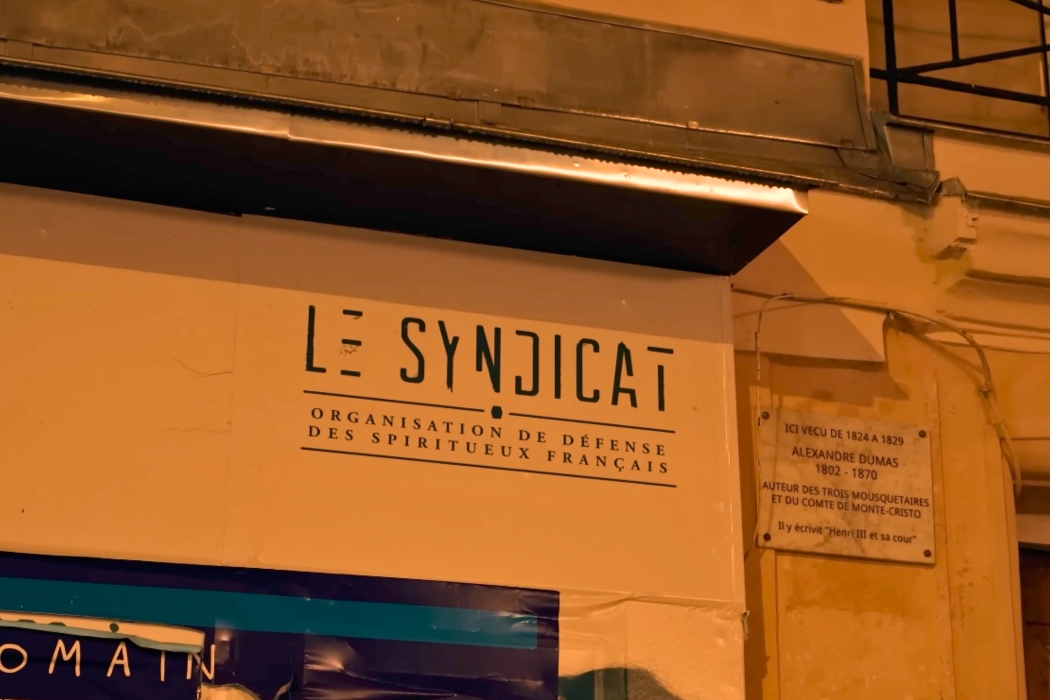 Close-up of the exterior signage and entrance for Le Syndicat cocktail bar in Paris.