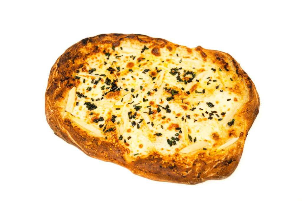 An overhead view of a rustic white asparagus pizza featuring blistered crust, fresh mozzarella, roasted garlic, and a heavy garnish of fresh chives.