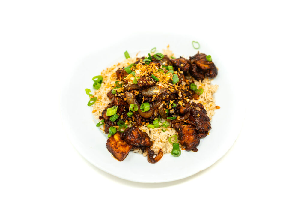 Overhead shot of Vietnamese BBQ chicken with charred pineapple coated in a dark palm sugar glaze, served over white rice with green onions.