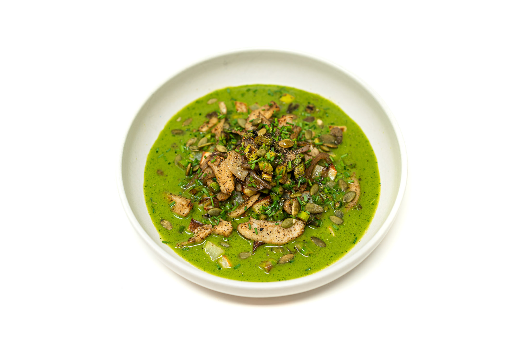 A shallow bowl filled with vibrant green pear aguachile, topped with a mound of wok-seared shaved chicken, diced apples, and toasted pepitas.